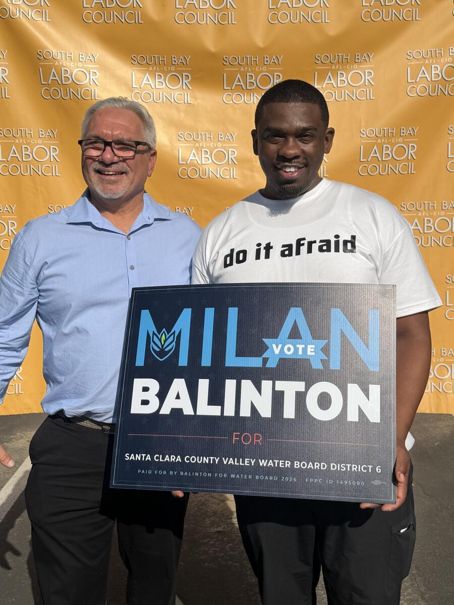 Milan Balinton and a supporter hold a campaign sign in front of a South Bay Labor Council banner