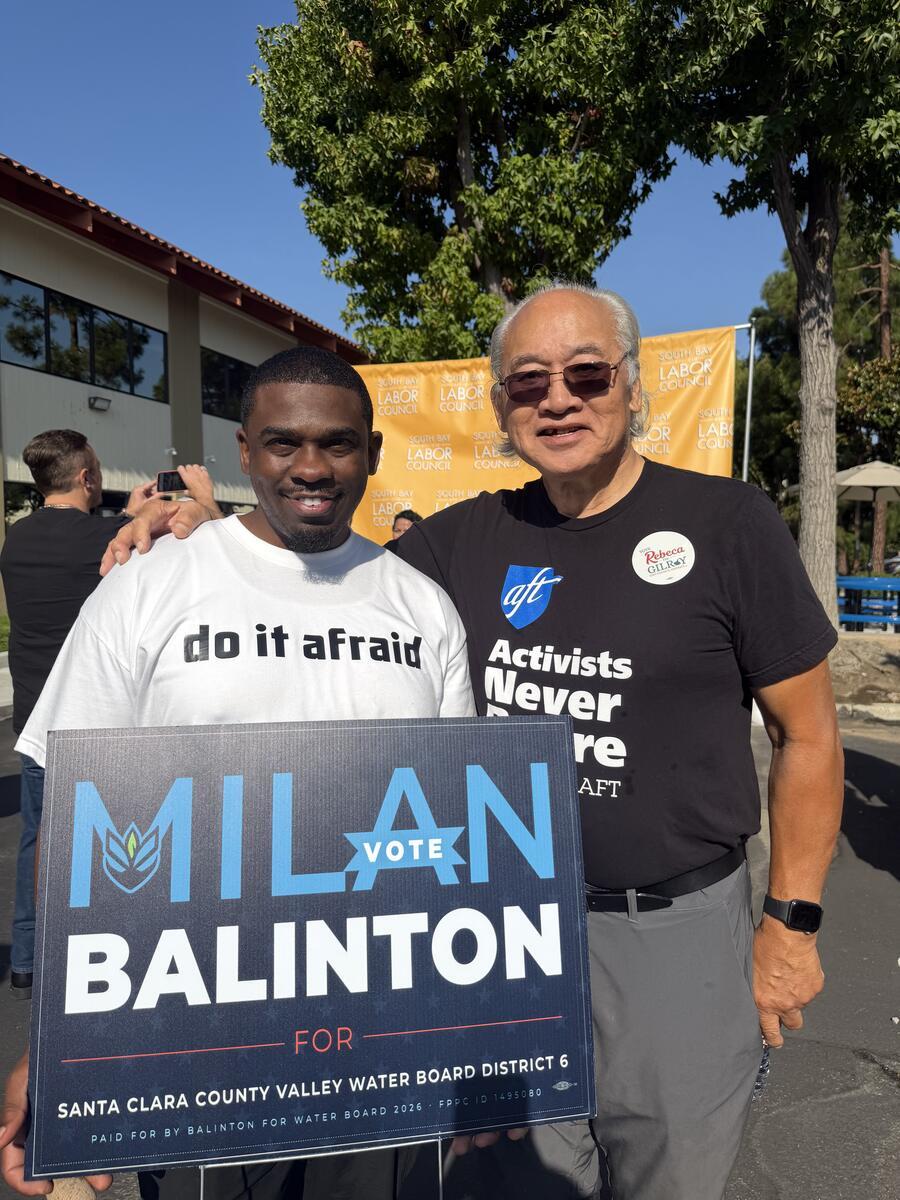 Milan Balinton holds a campaign sign beside a supporter at a South Bay Labor Council event