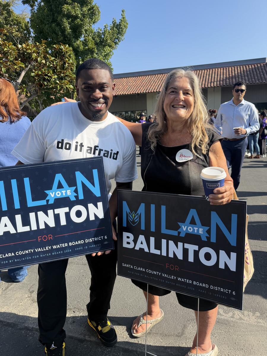 Milan Balinton and a supporter each hold a campaign sign outdoors
