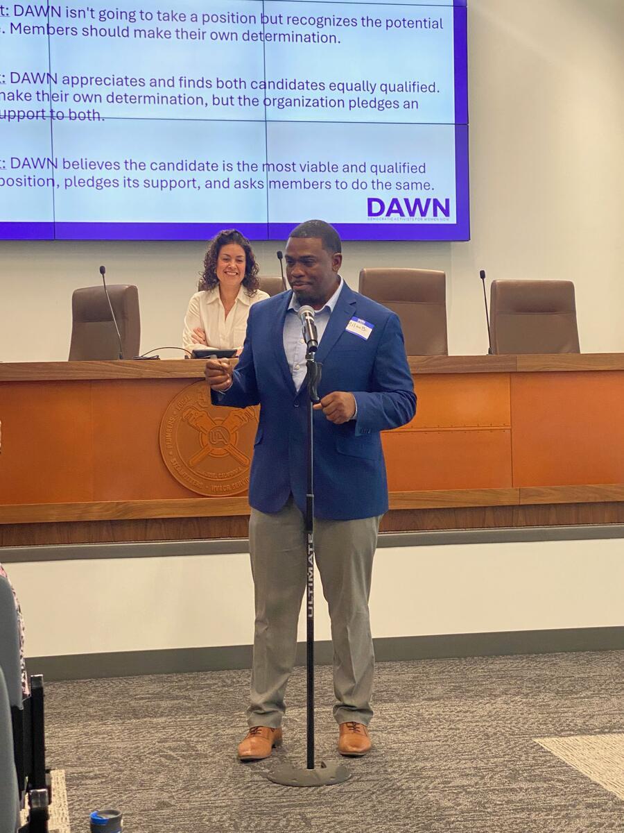 Milan Balinton speaks at a microphone in a council chamber during a DAWN endorsement meeting