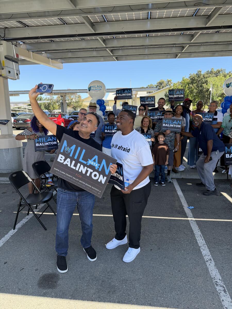 Milan Balinton and a supporter pose with a campaign sign as the crowd behind them holds signs