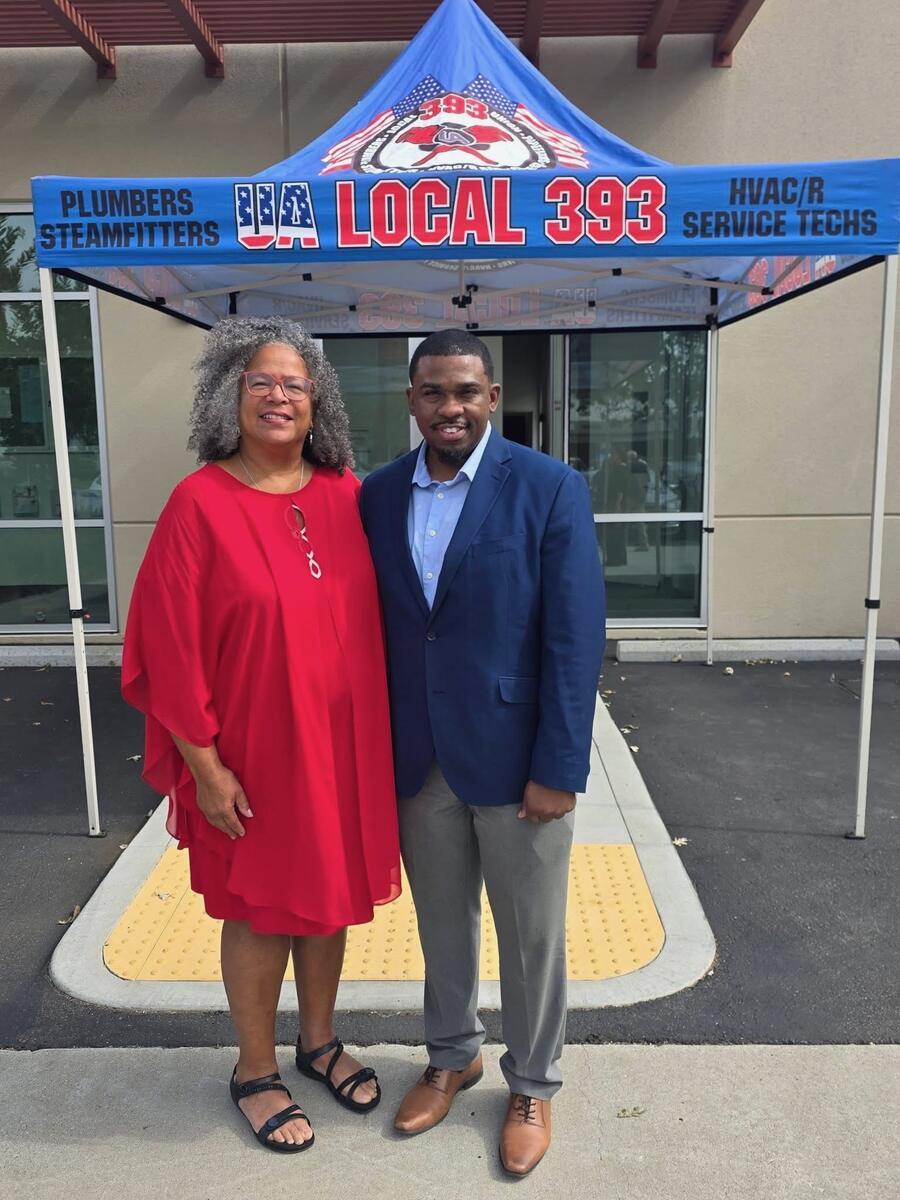Milan Balinton stands with a supporter under a Plumbers and Steamfitters Local 393 tent
