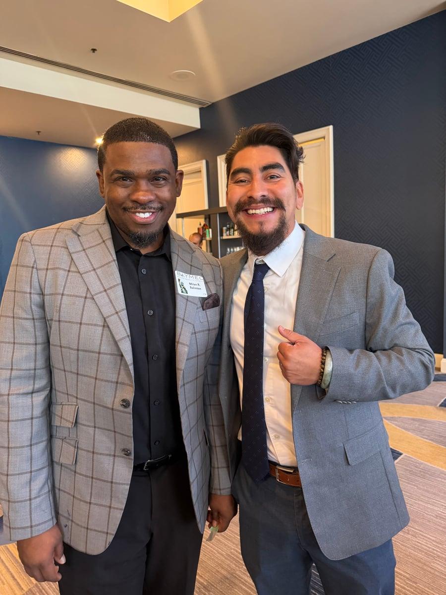 Milan Balinton with an event guest in a gray suit at a BAYMEC gathering